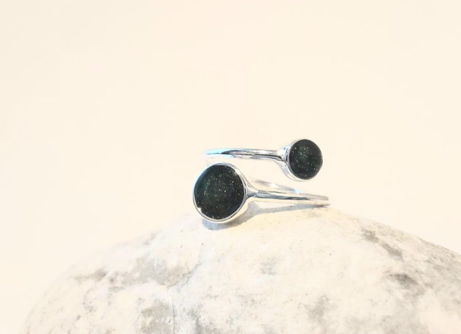 Two silver rings with black circular stones on a light grey surface.